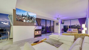 Una sala de estar moderna con chimenea, un sofá, una zona de comedor y vistas a la ciudad.