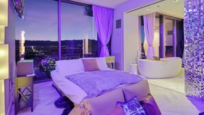 Un dormitorio moderno con una cama grande, un tocador con bañera y vistas a la ciudad.