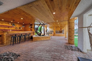 A spacious indoor area with a wooden bar, seating, and a central tree planter.
