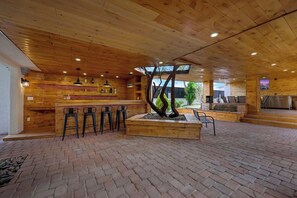 A wooden interior with a bar area, seating, and a central plant.