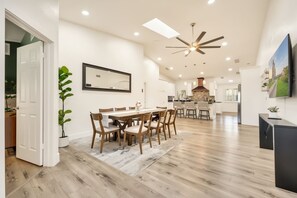 Une cuisine spacieuse dotĂ©e dâun Ăźlot central, dâun coin repas avec une longue table et des chaises, et dâun ventilateur de plafond.
