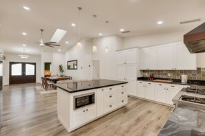 A modern kitchen with white cabinets, a central island, and a dining area with a table and chairs.