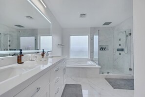 Une salle de bain moderne avec un grand miroir, un meuble-lavabo blanc et une douche Ă parois de verre.