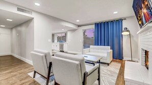 Uma sala de estar moderna com sofá, cadeiras, mesa de jantar e lareira.