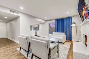 Una sala de estar moderna con sofá, sillones, una mesa de comedor y una chimenea.