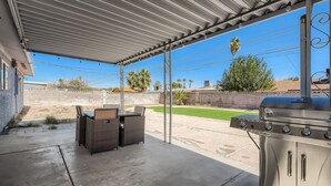 A covered patio with outdoor furniture and a barbecue grill. - Cheerful Home with Game Room! 10 Min to Strip! (Las Vegas)