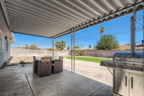 A covered patio with outdoor furniture and a barbecue grill.