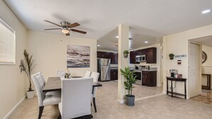 A modern kitchen with dark cabinets, stainless steel appliances, and a dining area with a table and chairs. - Cheerful Home with Game Room! 10 Min to Strip! (Las Vegas)