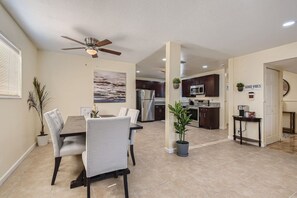 A modern kitchen with dark cabinets, stainless steel appliances, and a dining area with a table and chairs.