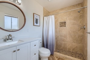 Une salle de bain équipée d’une douche, de toilettes, d’un lavabo et d’un miroir.