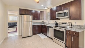 A modern kitchen with dark wood cabinets, stainless steel appliances, and a granite countertop. - Cheerful Home with Game Room! 10 Min to Strip! (Las Vegas)