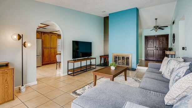 Uma sala de estar com sofá, televisão, mesa de centro e lareira.