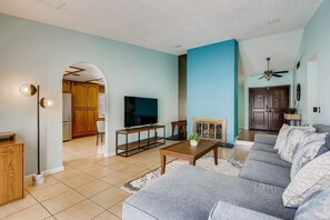 A living room with a sofa, TV, coffee table, and a fireplace. - Peaceful Family Getaway Centrally Located! (Las Vegas)