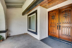 A building entrance with a concrete porch, a window with shutters, and a wooden double door with a keypad lock. - Peaceful Family Getaway Centrally Located! (Las Vegas)