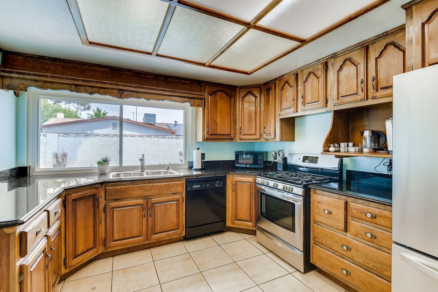 A kitchen with wooden cabinets, a stainless steel stove, a dishwasher, and a refrigerator.