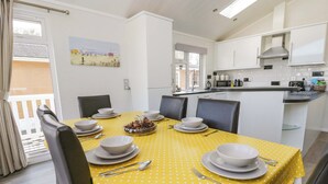 Un coin repas avec une nappe jaune, des assiettes blanches et des chaises noires.