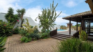 A courtyard with a pool, surrounded by various plants and a wooden deck.