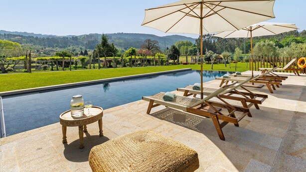 Un espace aménagé au bord de la piscine, avec des chaises longues, une table et un parasol.