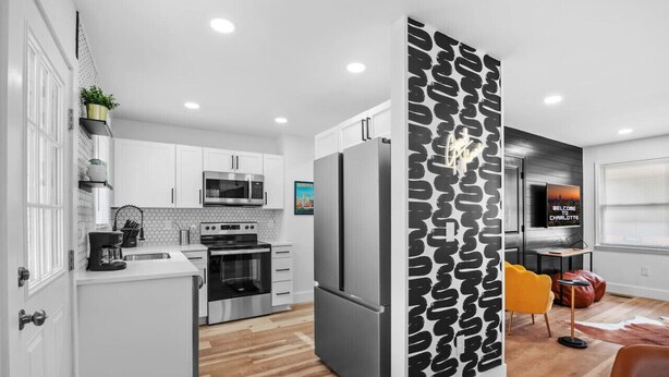 A modern kitchen with white cabinets, stainless steel appliances, and a black patterned partition.