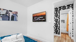 A hotel room with a cityscape TV, a blue bedspread, and a patterned door.