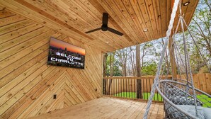 A wooden deck with a hanging chair, a ceiling fan, and a welcome sign.