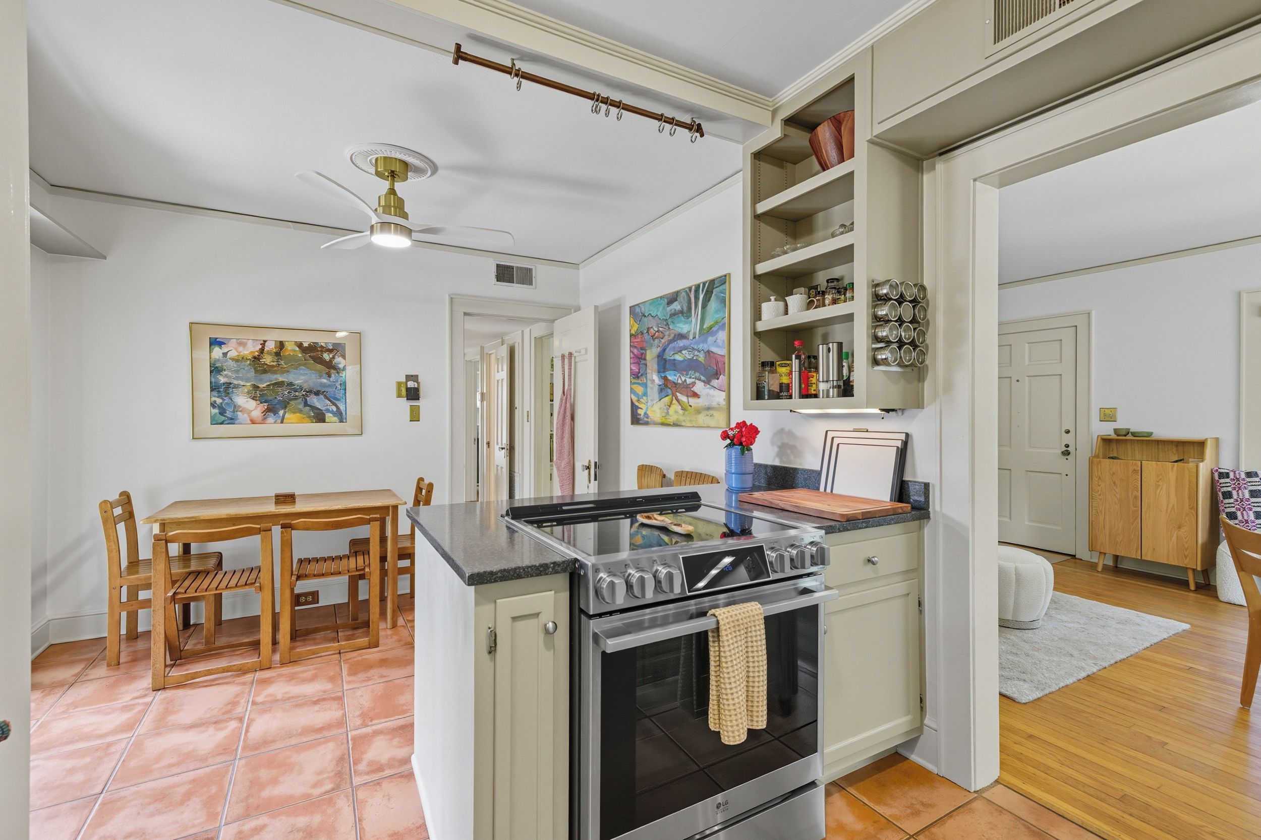 A kitchen with a central island, dining table, chairs, and a ceiling fan.