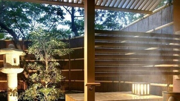 A hot spring area with a wooden deck, a stone lantern, and a large hot spring bath. - Awara Onsen Mimatsu (Awara)
