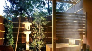 A wooden deck with a hot tub, a stone lantern, and a wooden chair. - Awara Onsen Mimatsu (Awara)