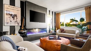 A modern living room with a fireplace, comfortable seating, a flat-screen TV, and a view of the outdoors. - Old Town's  Luxury Oasis - 16+ Guests, Designed for entertainment & relaxation. (Scottsdale)