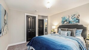 A bedroom with a large bed, a dark door, and two wall-mounted paintings. - Cozy 2-bedroom bungalow in cozy East Point GA 15 mins from downtown Atlanta (East Point)
