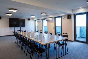 A conference room with a long table, chairs, a flat-screen TV, and large windows. - Gino Seaside Tbilisi, Trademark Collection by Wyndham (Tbilisi)