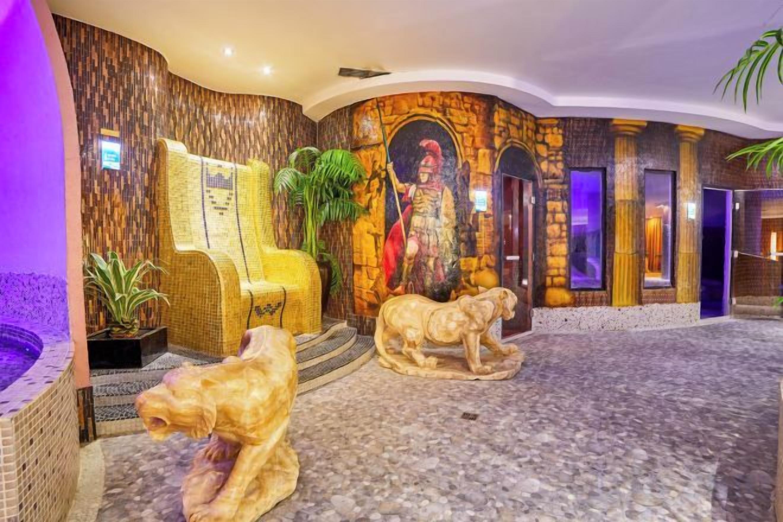 Un vestíbulo con un sillón grande, una estatua y un mural.