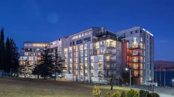 Un hotel de varios pisos con un diseño moderno, que cuenta con balcones en los pisos superiores y una fachada bien iluminada.