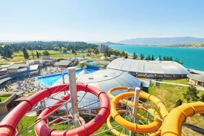 Un parc aquatique doté de nombreux toboggans et d’un espace piscine, entouré de bâtiments et offrant une vue sur la mer.