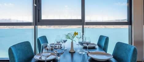 A dining table set for four with a view of the sea and a distant cityscape.