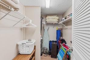 A laundry room with a drying rack, a basket, and a fan.