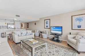 A modern living room with a sofa, coffee table, and a television displaying a beach scene.