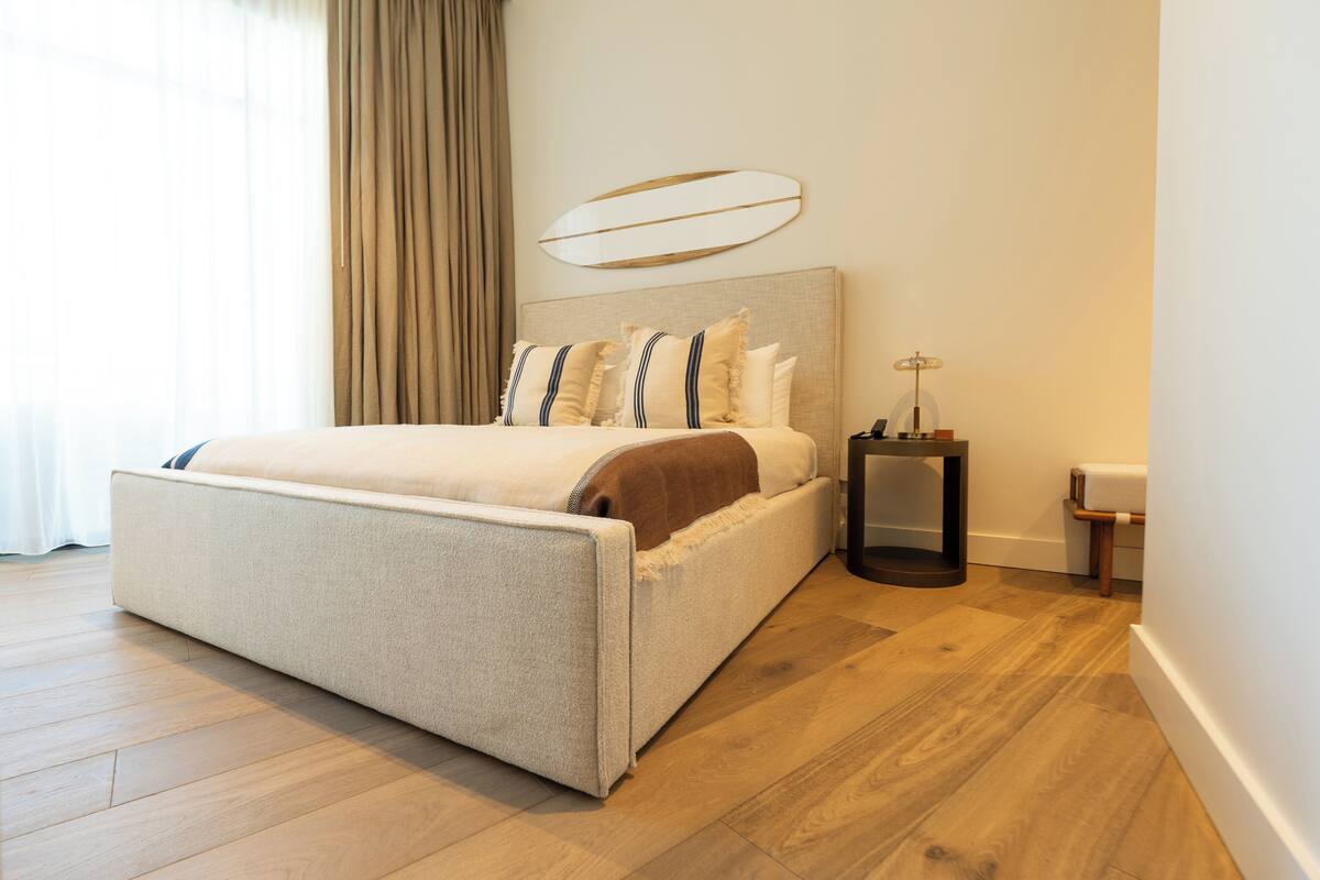 Une chambre à coucher moderne avec un grand lit, une table de chevet et un luminaire fixé au mur.