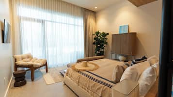 Une chambre moderne avec un grand lit, une chaise, une plante et un meuble.