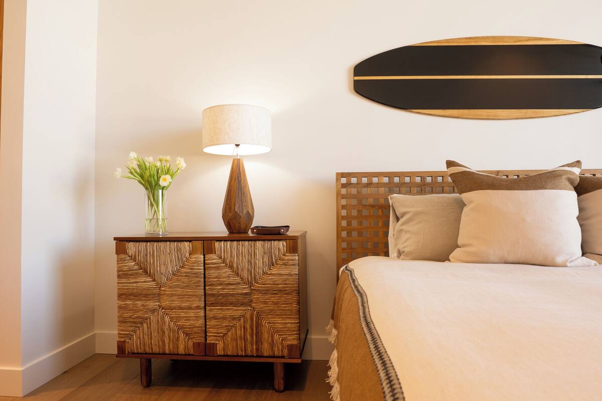 Une chambre à coucher avec une tête de lit en bois, une table de chevet avec une lampe et un lit avec des oreillers.