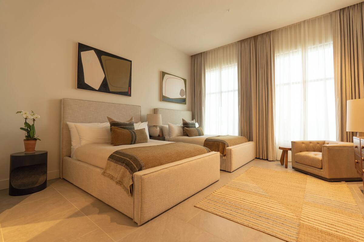 Une chambre d’hôtel avec un lit, un canapé, une chaise, une lampe et une plante en pot.
