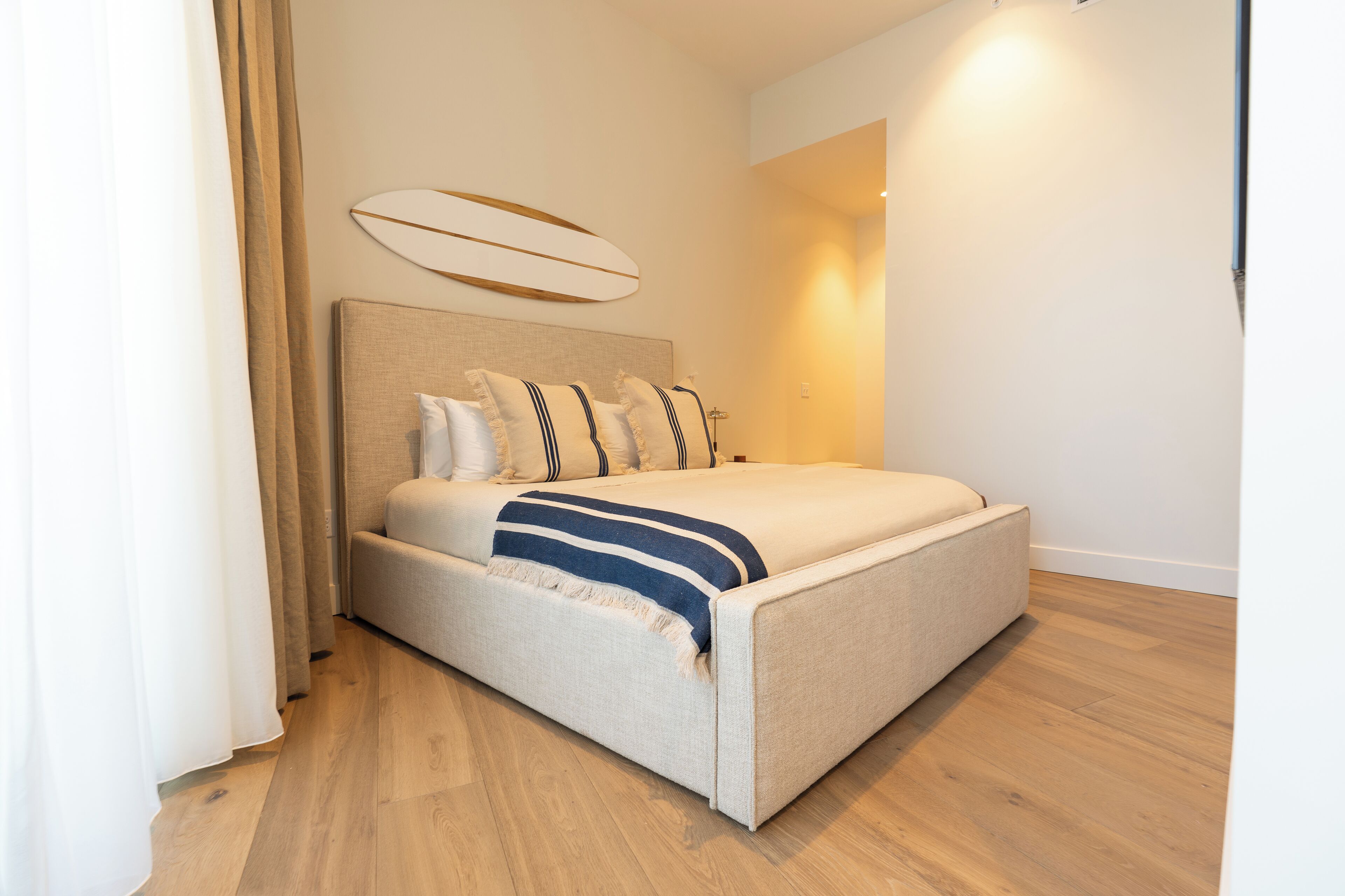 A modern bedroom with a large bed, a headboard with a decorative panel, and a bedside table with a lamp.