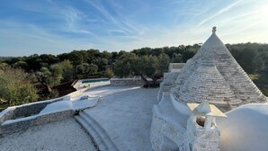 A stone-roofed building with a pool and a view of the surrounding landscape. - Casa Pampini. A stunning villa set in beautiful Valle d’Itria with private pool (Ceglie Messapica)