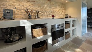 A kitchen with a stone wall, built-in shelves, and a coffee machine. - Casa Pampini. A stunning villa set in beautiful Valle d’Itria with private pool (Ceglie Messapica)