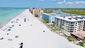 Une plage avec un hôtel, un ciel dégagé et une rivière en arrière-plan.