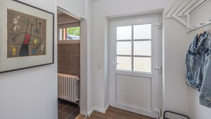 A hallway with a white door, a radiator, and a framed abstract painting.