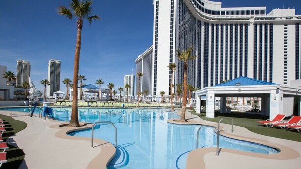 A hotel pool area with multiple swimming pools, palm trees, and a large building in the background. - Westgate Resort & Casino Las Vegas 1-bedroom (Las Vegas)