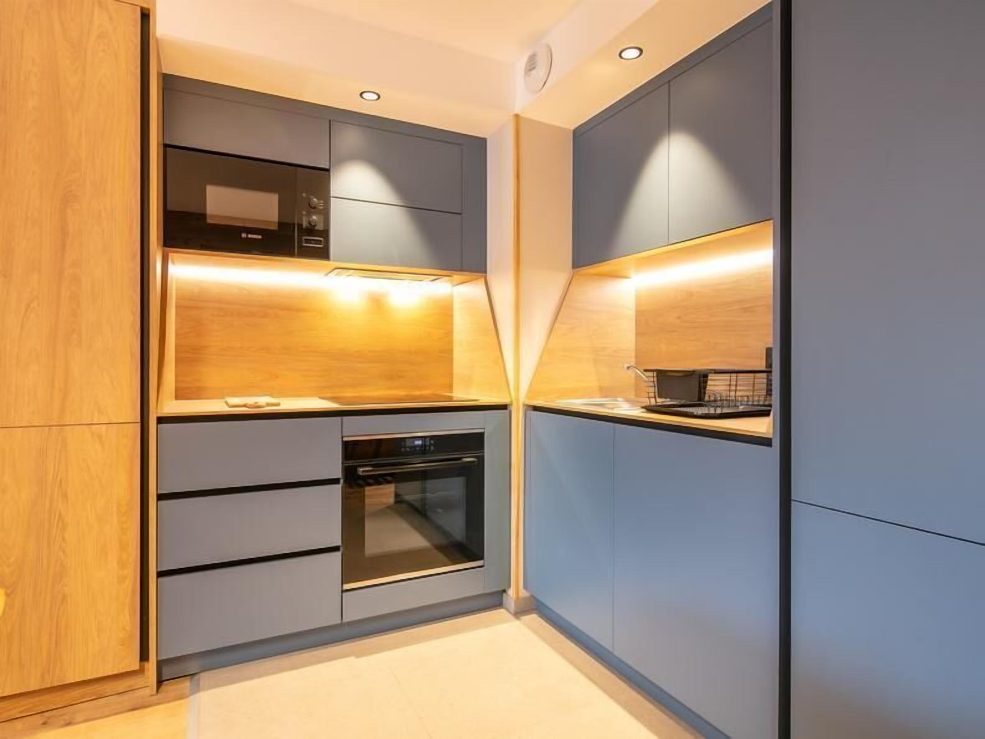 A modern kitchen with built-in appliances, a microwave, oven, and a sink.