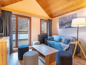 A cozy living room with a sofa, ottomans, a coffee table, a TV, and a painting on the wall. - Wifi, 150m from resort center, swimming pool, sauna, hammam, balcony, parking, tv, ski locker, 104m² (Vaujany)