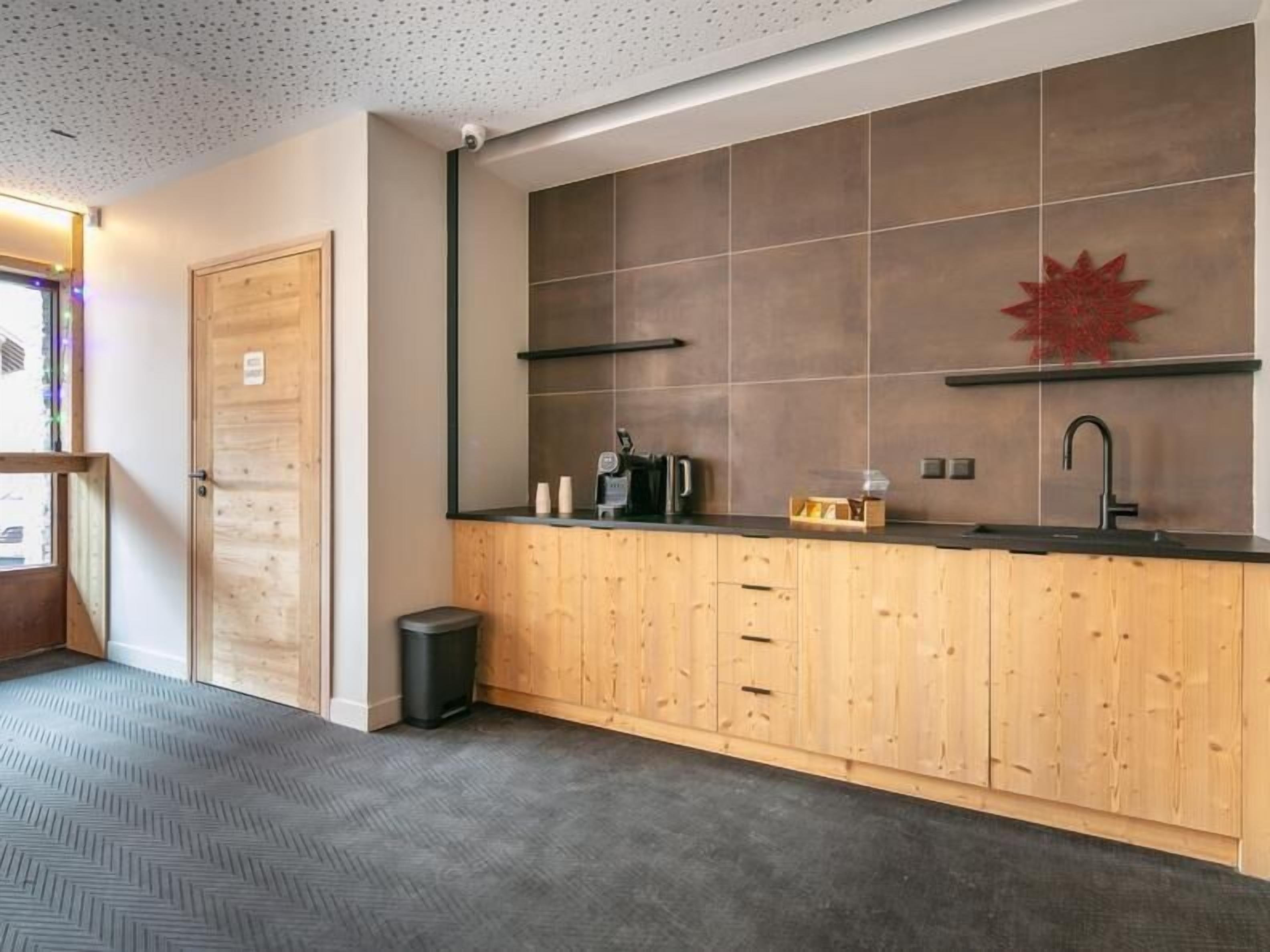 A modern kitchen with wooden cabinets, a black countertop, and a red decorative element on the wall.